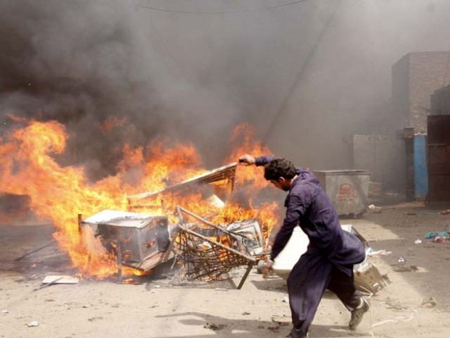 A Deobandi militant of ASWJ burns belongings from Christian houses in Lahore on Saturday. 