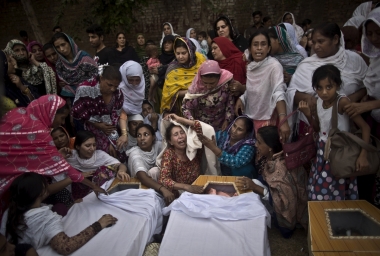 Pakistani women grieve over the coffins of their relatives, who were killed in a suicide attack on a church, in Peshawar, Pakistan, 22 September 2013.