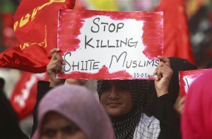 A woman holds a sign amidst hundreds of Pakistani followers of Shia Islam protesting against targeted killings of Shia Muslims in Karachi