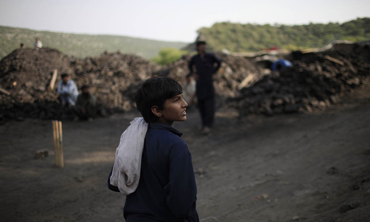 Samiullah watches the other miners play cricket at a coalfield in Choa Saidan Shah, Punjab province