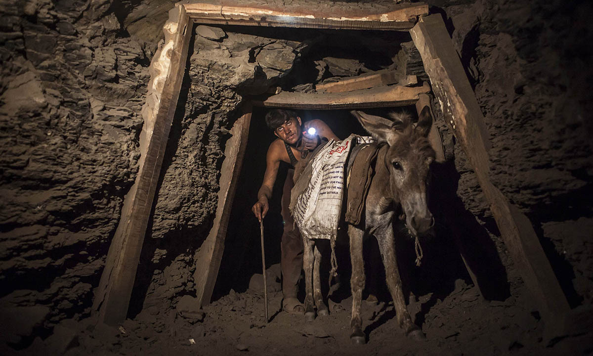 A miner with a donkey makes his way through the tunnel leading out of a coal mine in Choa Saidan Shah in Punjab province