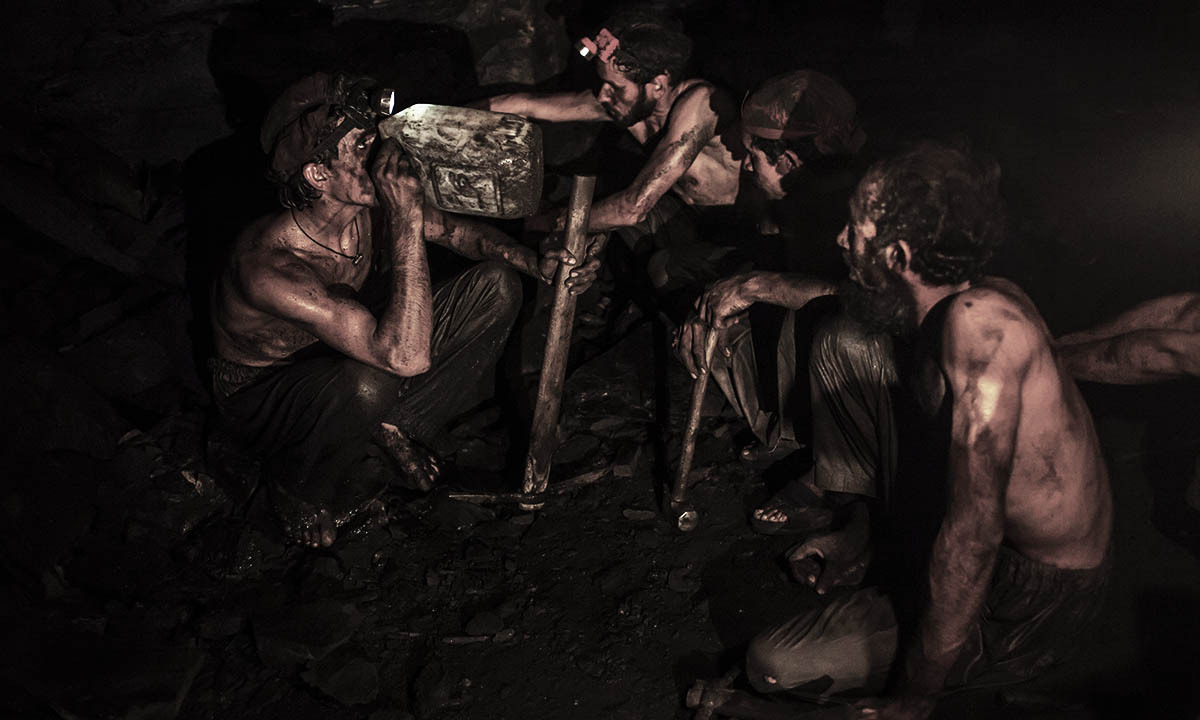 Miners take a break to drink water inside a coal mine in Choa Saidan Shah, Punjab province