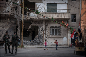 Syrian soldiers and children at a checkpoint in the besieged and devastated city of Homs, Syria, March 23, 2014. For both sides of Syria's civil war, Homs, a central Syrian crossroads with a diverse prewar population of 1 million, is crucial to the future. (Sergey Ponomarev / The New York Times)