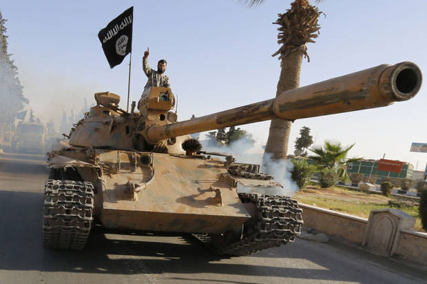 Militant Islamist fighters on a tank take part in a military parade along the streets of northern Raqqa province June 30, 2014. Militant Islamist fighters held a parade in Syria's northern Raqqa province to celebrate their declaration of an Islamic "caliphate" after the group captured territory in neighbouring Iraq, a monitoring service said. The Islamic State, an al Qaeda offshoot previously known as Islamic State in Iraq and the Levant (ISIL), posted pictures online on Sunday of people waving black flags from cars and holding guns in the air, the SITE monitoring service said. REUTERS/Stringer (SYRIA - Tags: POLITICS CIVIL UNREST CONFLICT) - RTR3WJA0